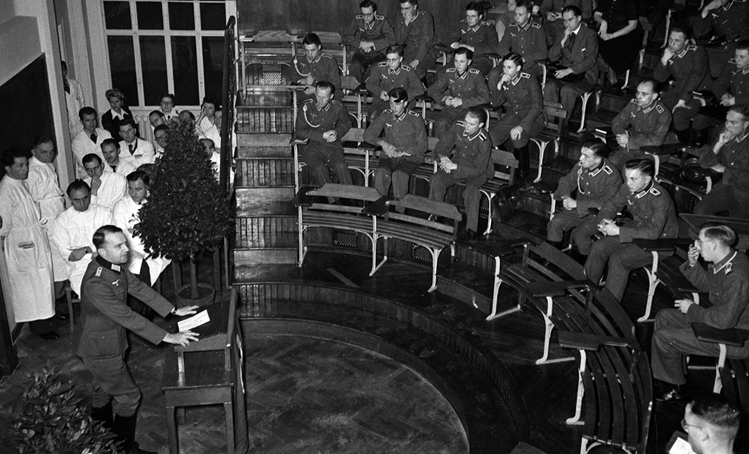 Cours inaugural de la Faculté de médecine de la RUS par le doyen Johannes Stein (au pupitre) dans l’amphithéâtre de la clinique médicale B (Medizinische Abteilung I), 24 novembre 1941. © Süddeutsche Zeitung.