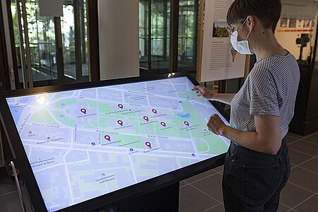 Delphine Issenmann, du Jardin des sciences, présente les lieux d’où sont issues les œuvres exposée, grâce à un tableau interactif