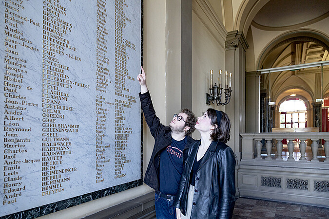 Quentin Bessonne et Laure Decker devant la plaque commémorative, dans l'entrée du Palais universitaire. © Catherine Schröder / Unistra