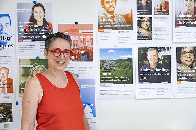 Charlotte Dorn devant quelques-une des affiches des événements organisés cette année universitaire 2024-2025 au Cuej. © Catherine Schröder / Unistra 